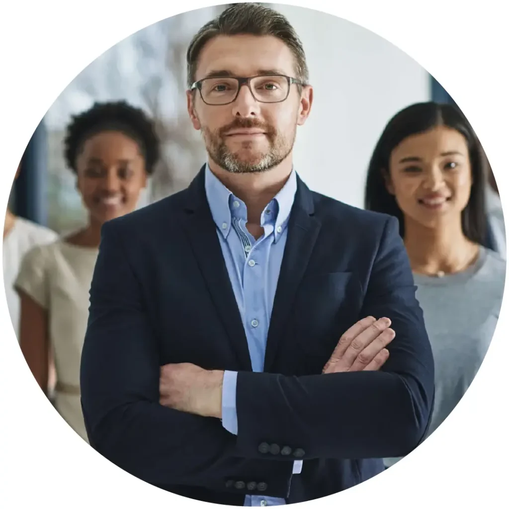 Confident male accounting manager with arms crossed, colleagues visible behind him