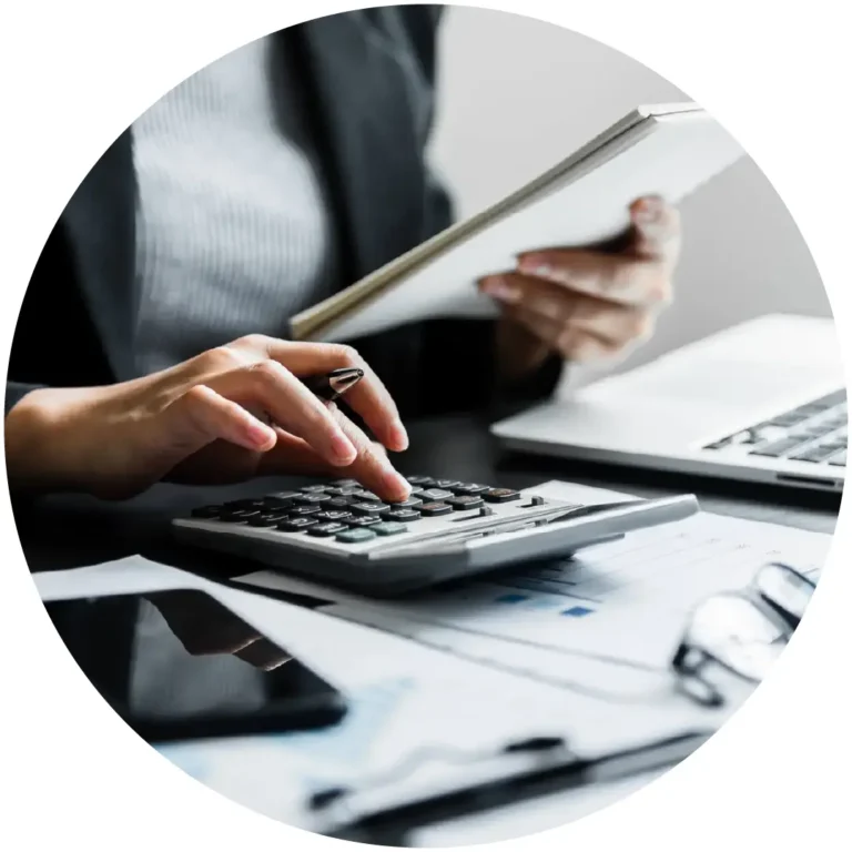 Hands working on a calculator and financial documents at a desk